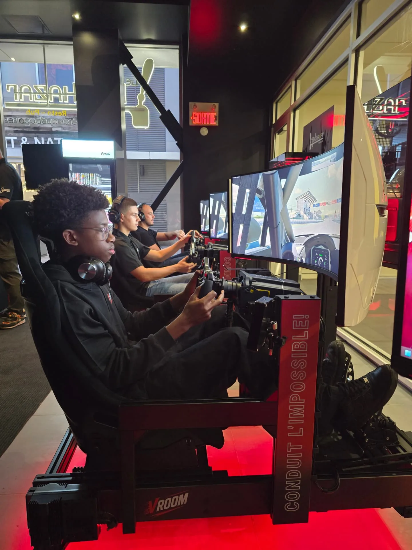 Drivers in the window-side simulator row at Vroom DIX30