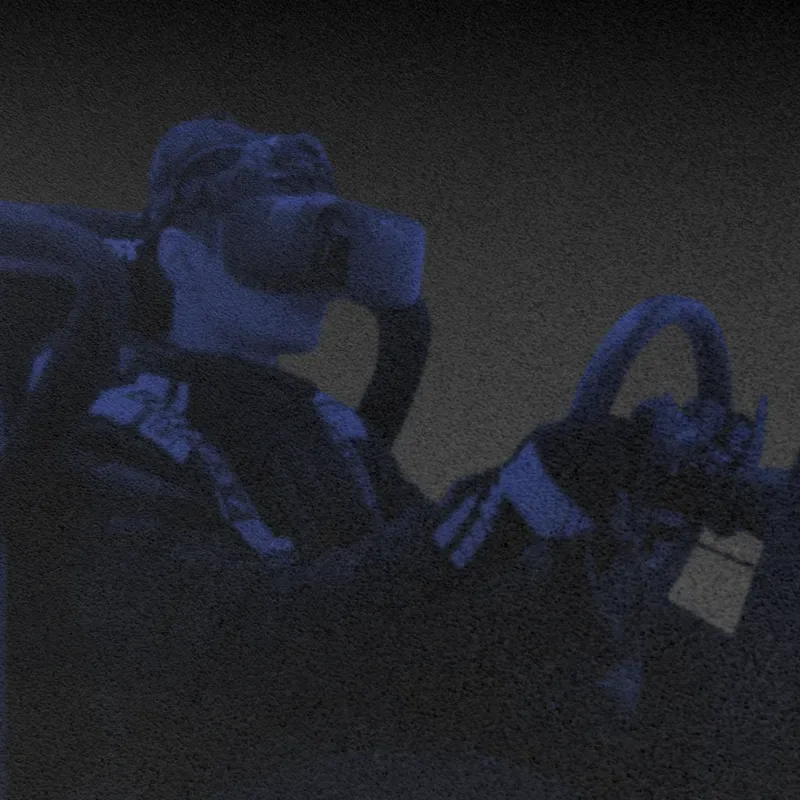 Driver wearing a VR headset in an N90s Grid racing cockpit.