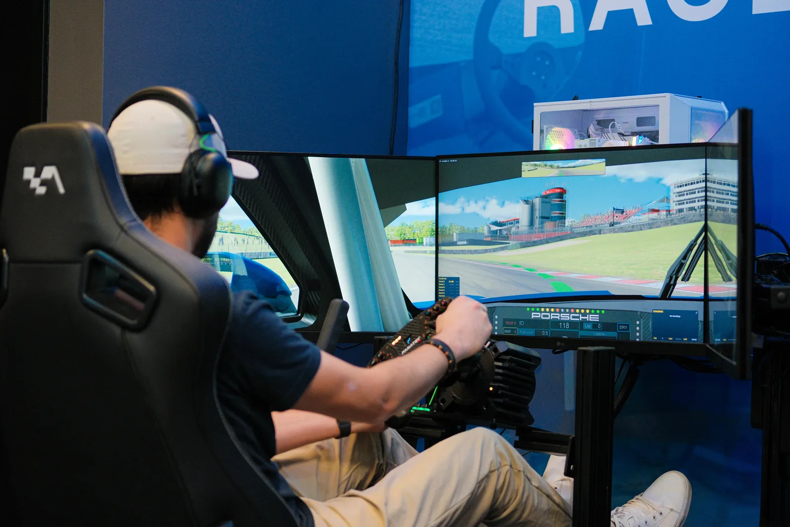 Driver using a triple-monitor racing simulator at TraqLab.